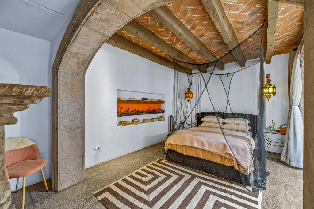 Casa Clae, bedroom with a canopy bed beneath a stone arch and a brick vault, San Miguel de Allende