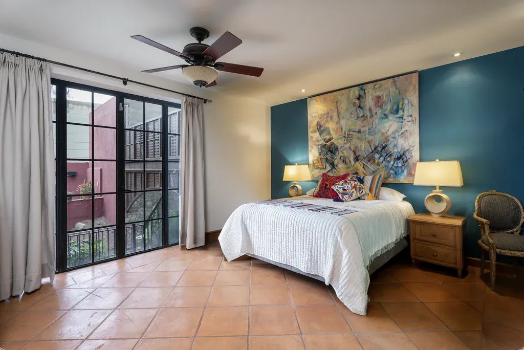 Casa del Arroyo, bedroom with steel-framed glass doors and a ceiling fan, San Miguel de Allende