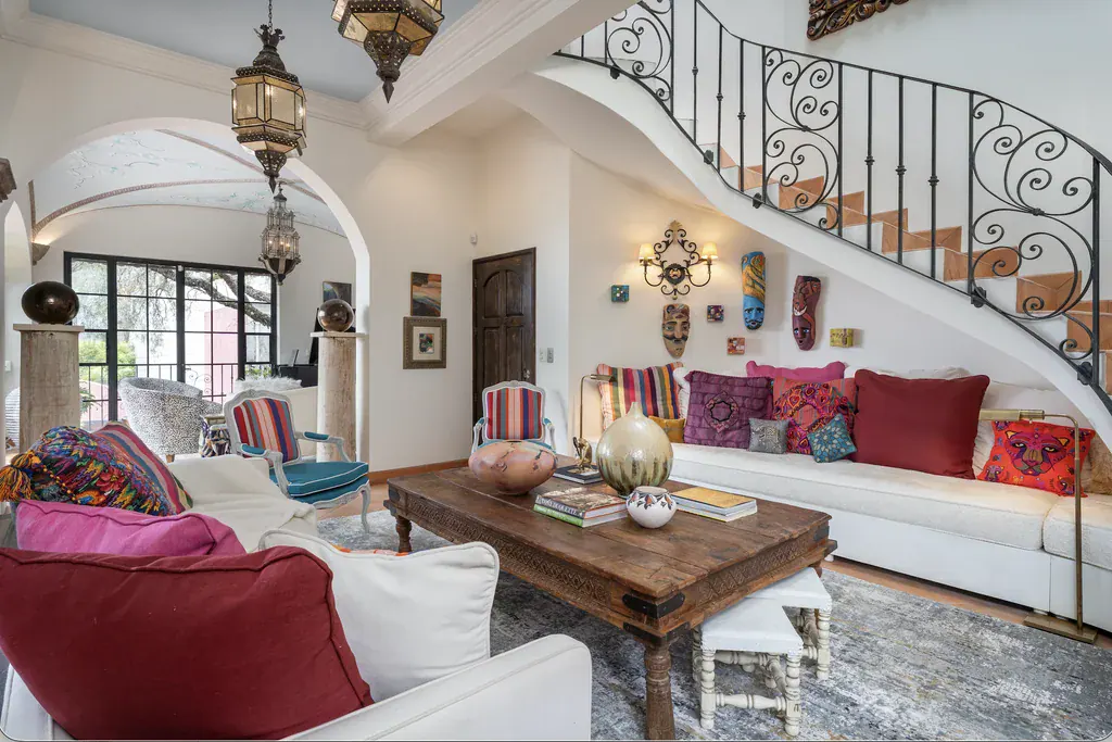 Casa del Arroyo, living room with a wrought-iron staircase and colorful cushions, San Miguel de Allende