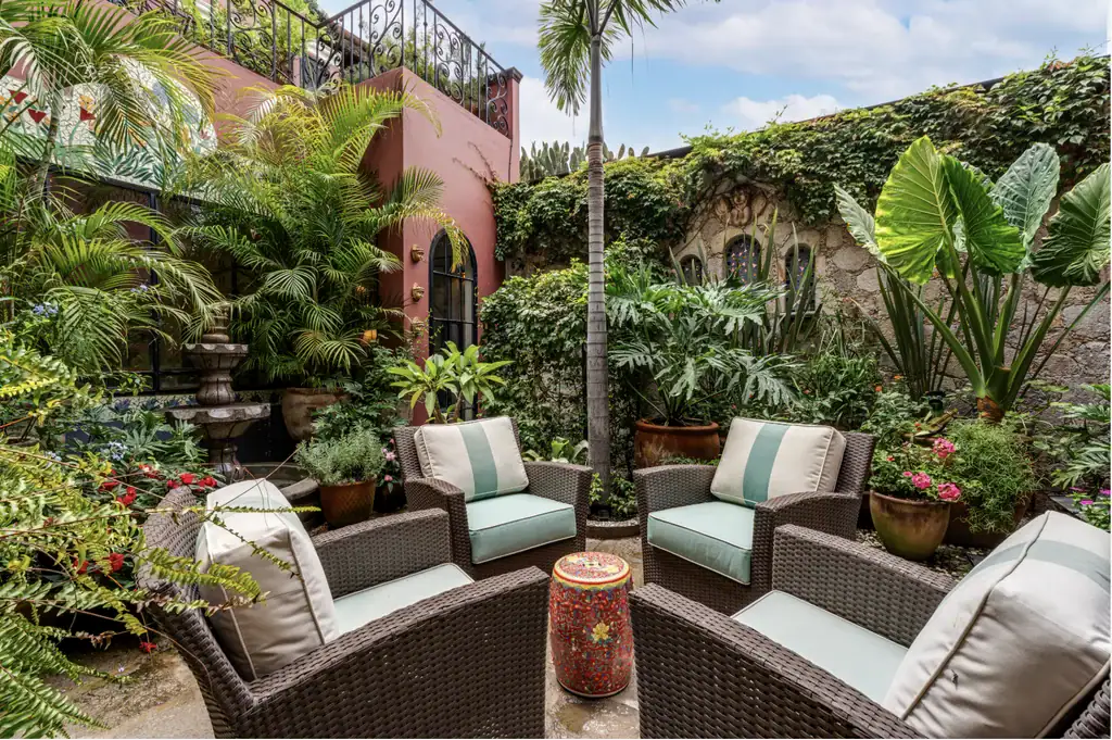 Casa del Arroyo, shaded garden courtyard with wicker seating and tropical plants, San Miguel de Allende