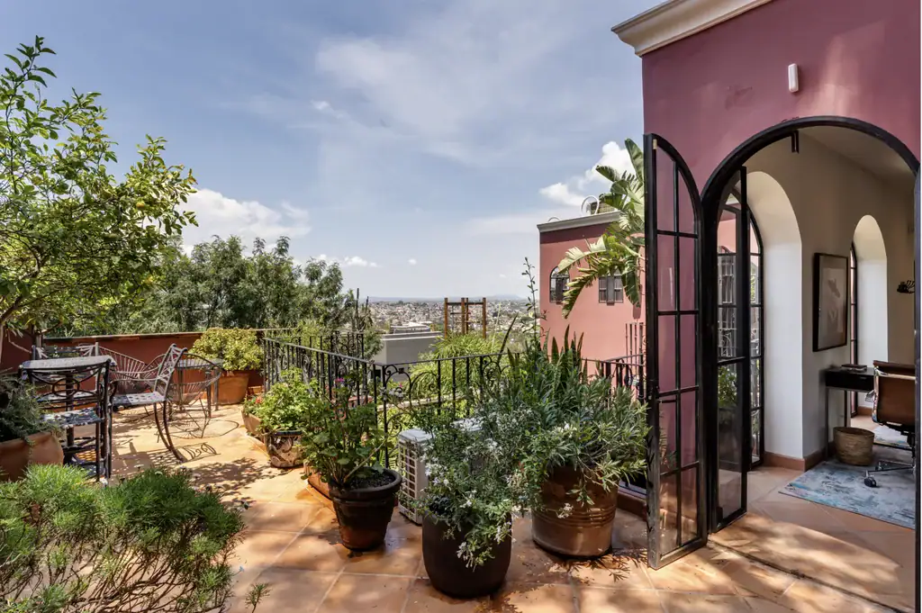 Casa del Arroyo, roof terrace with potted plants and an open arched door, San Miguel de Allende