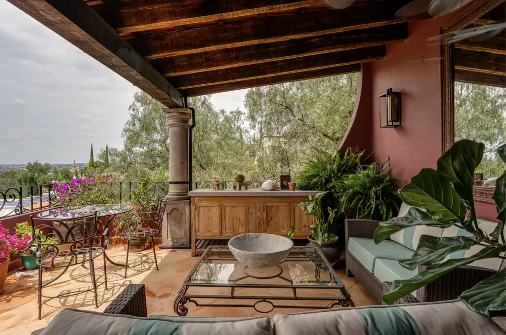 Casa del Arroyo, covered terrace with a stone-columned portico and wicker seating, San Miguel de Allende
