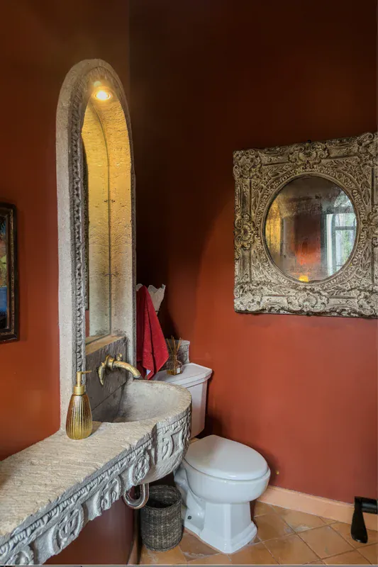 Casa del Arroyo, powder room with a red wall and an ornate mirror, San Miguel de Allende