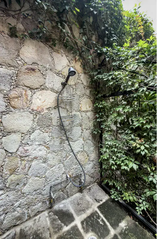 Casa del Arroyo, outdoor shower on a stone wall covered in vines, San Miguel de Allende
