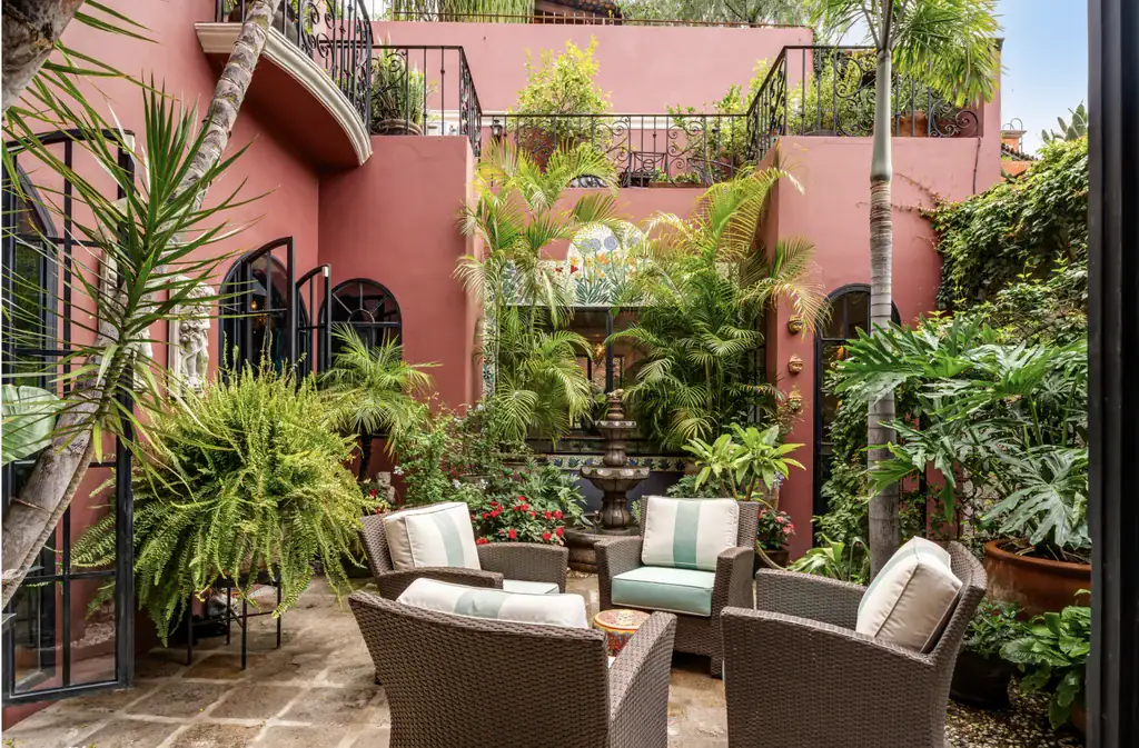 Casa del Arroyo, courtyard with wicker armchairs, ferns and a terracotta-colored wall, San Miguel de Allende