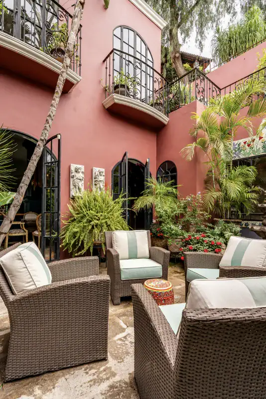 Casa del Arroyo, courtyard seating area beneath balconies and tropical plants, San Miguel de Allende