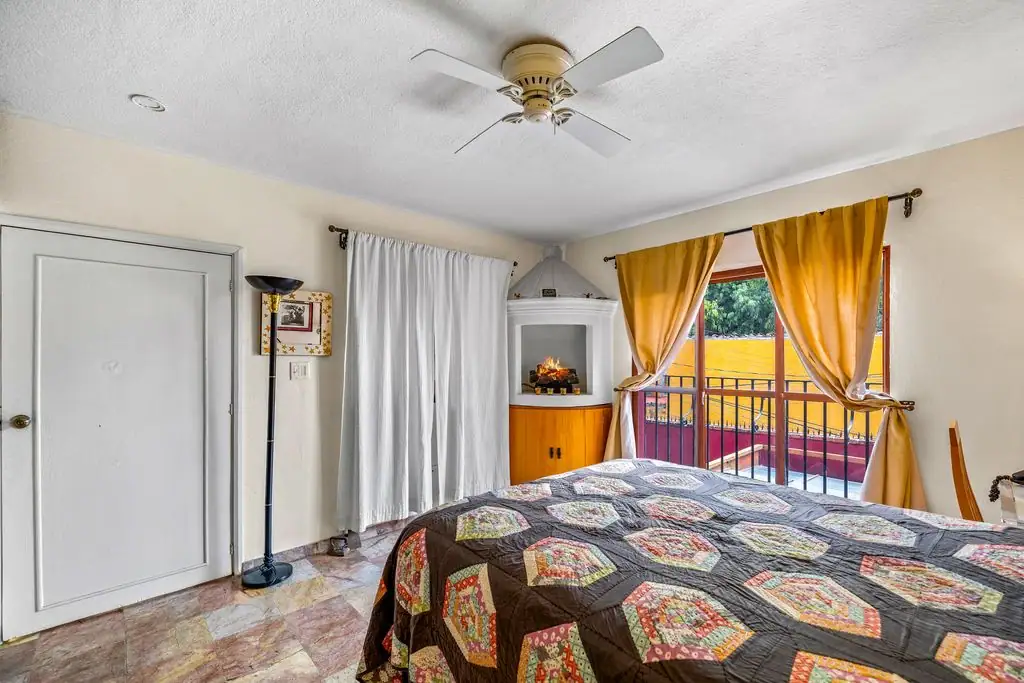 Cozy bedroom with a patchwork quilted bed, white closet door, and a balcony balcony door framed by yellow curtains, San Miguel de Allende