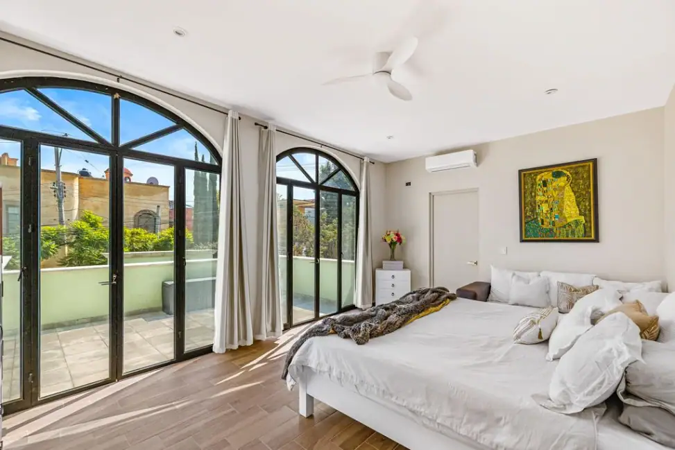 Casa Angel, primary bedroom with arched glass doors and a framed painting, San Miguel de Allende