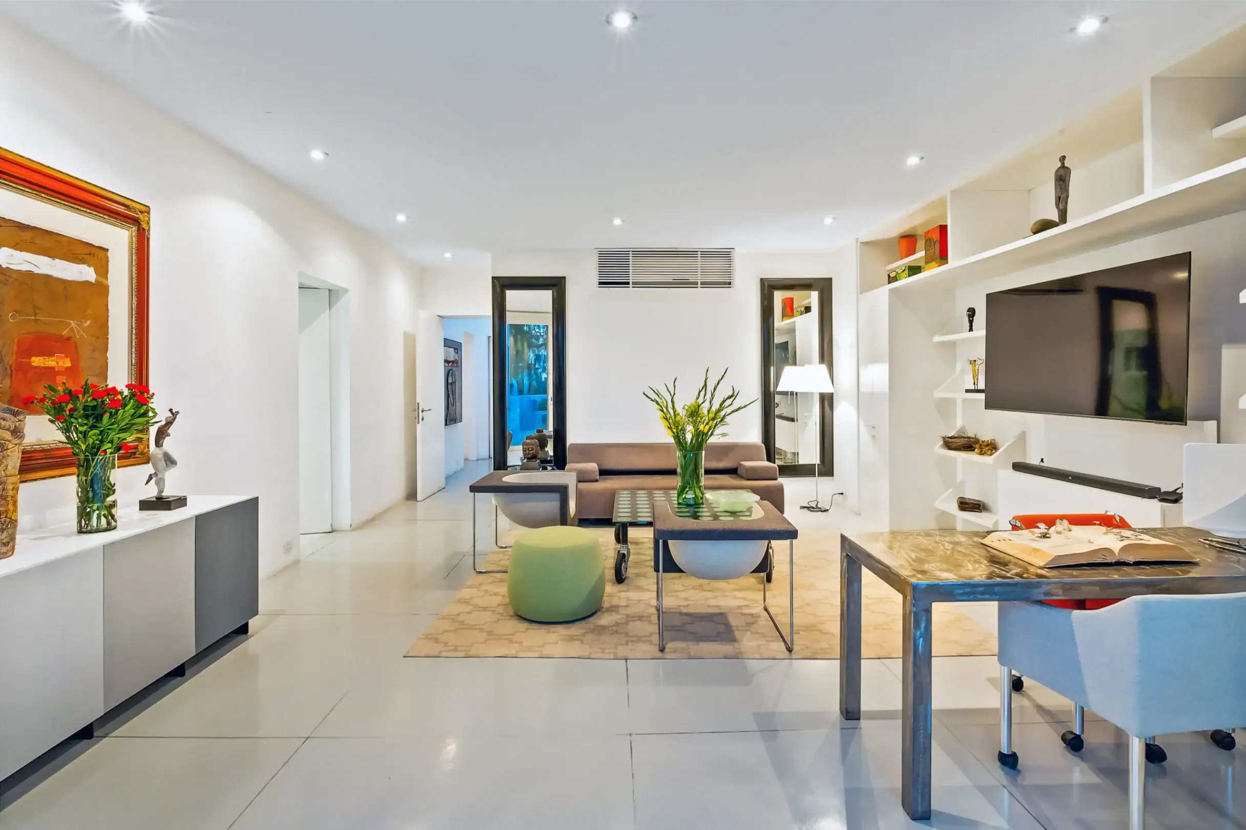 Bright modern living room with white walls, built-in shelving, a wall-mounted TV, and a central seating area, San Miguel de Allende