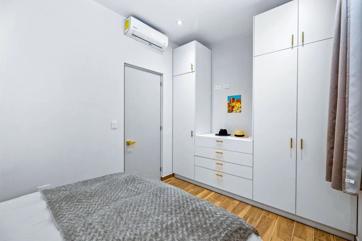 Casas Angel & Angelito, bedroom with white built-in wardrobes and a wall-mounted air conditioner, San Miguel de Allende