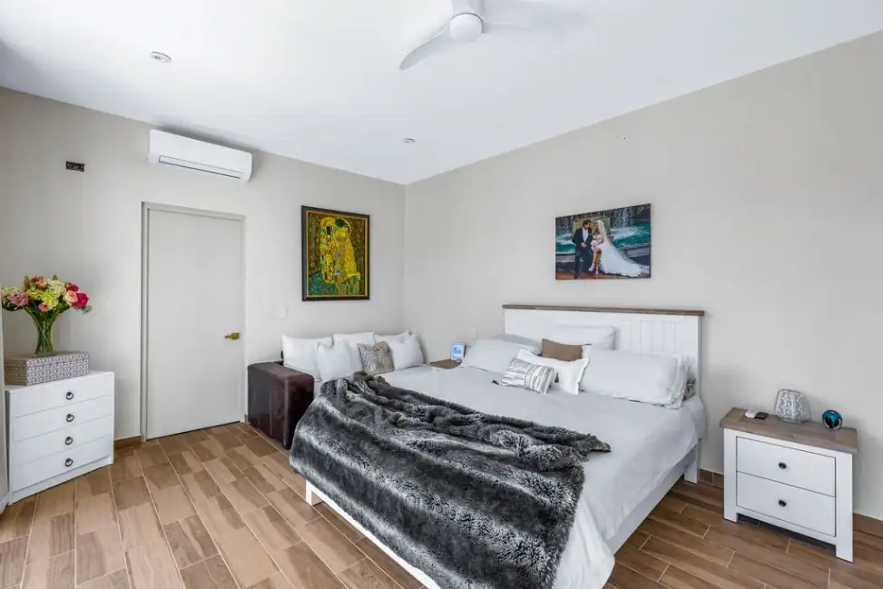 Casa Angel, primary bedroom with a white bed, gray throw and wall-mounted air conditioner, San Miguel de Allende