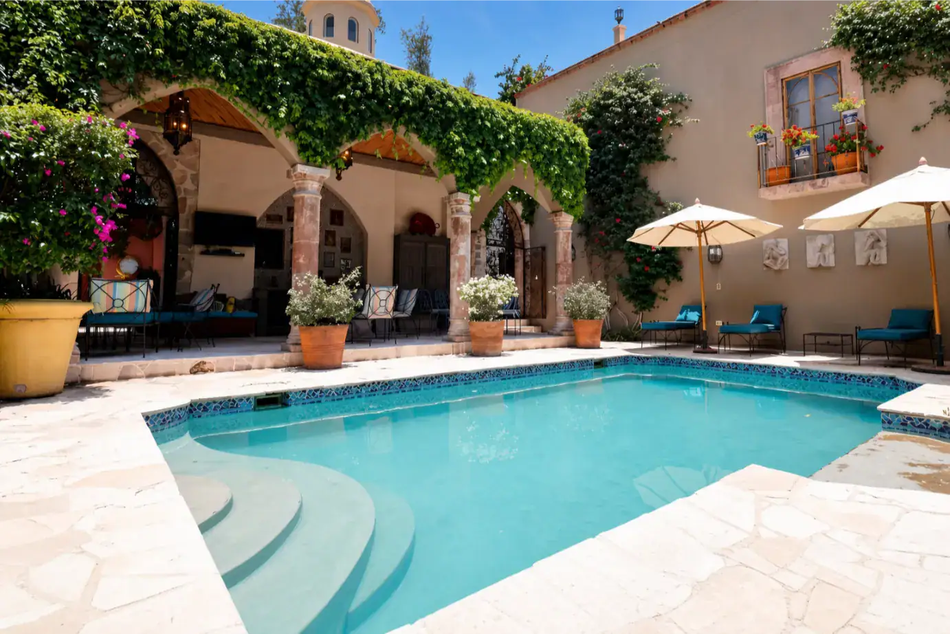 Poolside courtyard with a turquoise rectangular pool, stone terrace, and vine-covered arches providing shaded seating, San Miguel de Allende