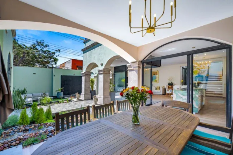 Casa Angel, outdoor wood dining table on the patio, with glass doors into the living room, San Miguel de Allende
