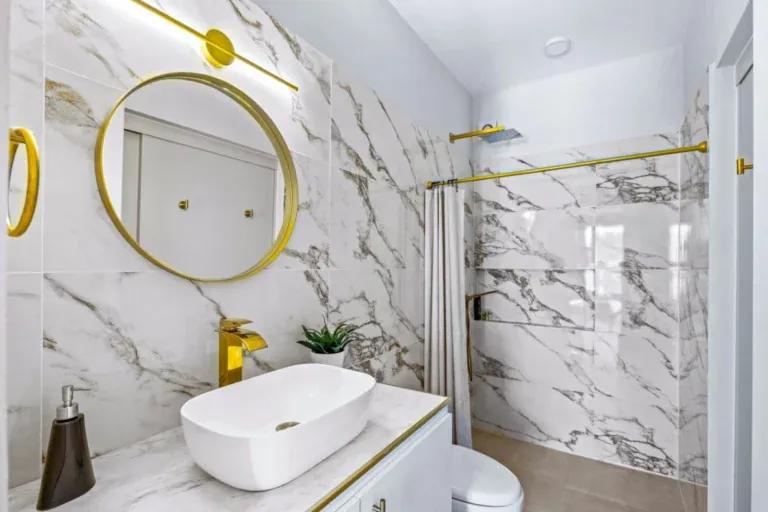 Casas Angel & Angelito, bathroom with a white marble shower and a round gold mirror, San Miguel de Allende