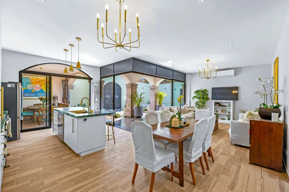 Casa Angel, open dining and living area with a gold chandelier and an arched glass partition, San Miguel de Allende