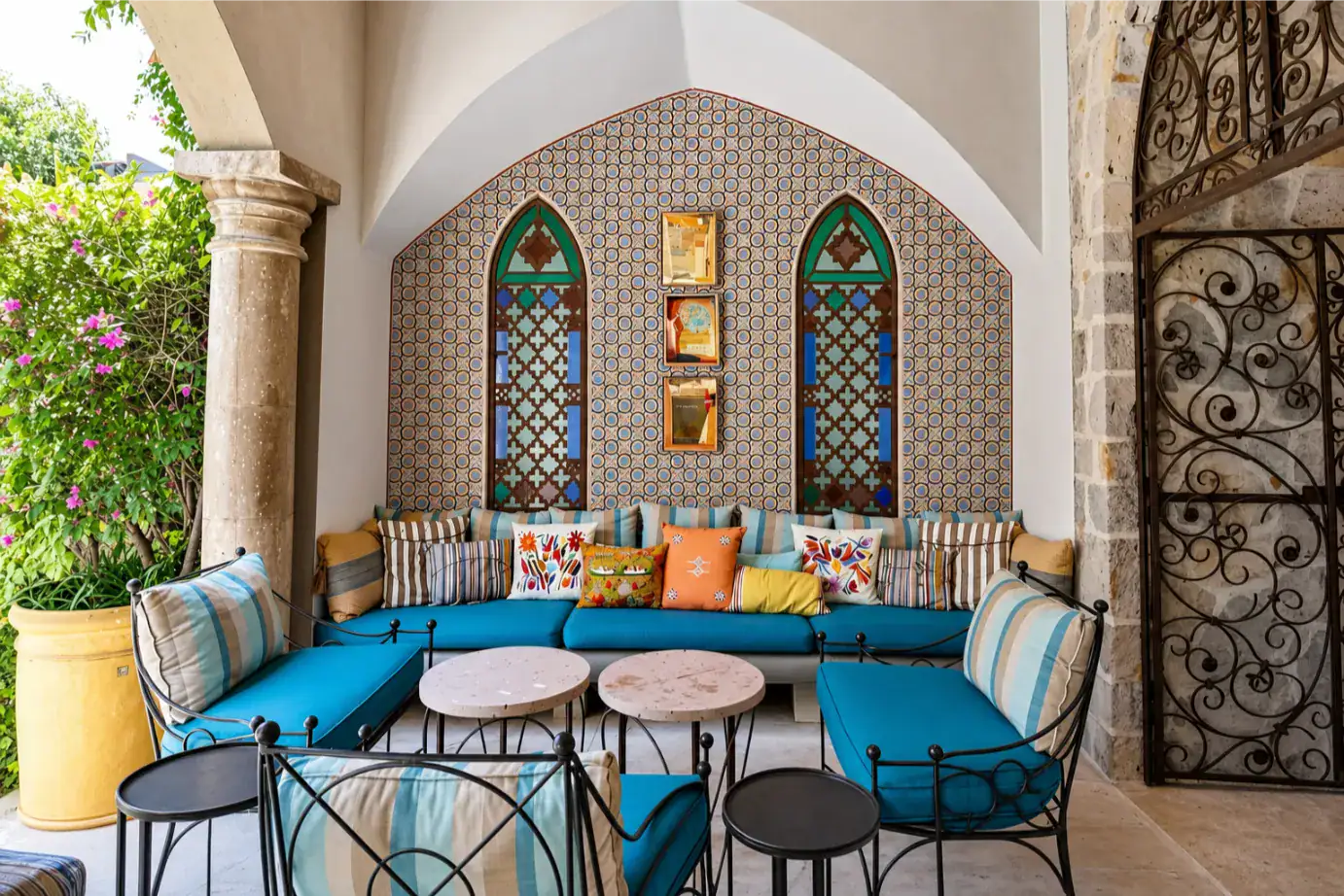 Outdoor seating area with turquoise cushions, colorful pillows, and a mosaic arched wall, San Miguel de Allende