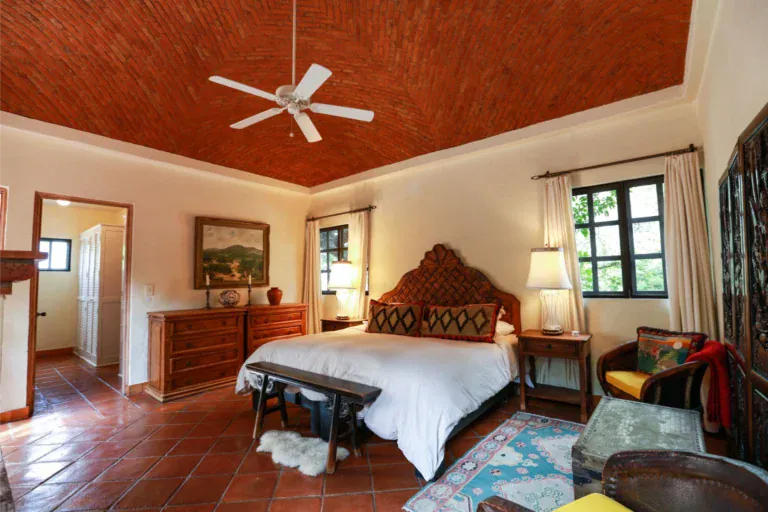 Casa Privada Baeza, primary bedroom with a brick vaulted ceiling and a carved headboard, San Miguel de Allende