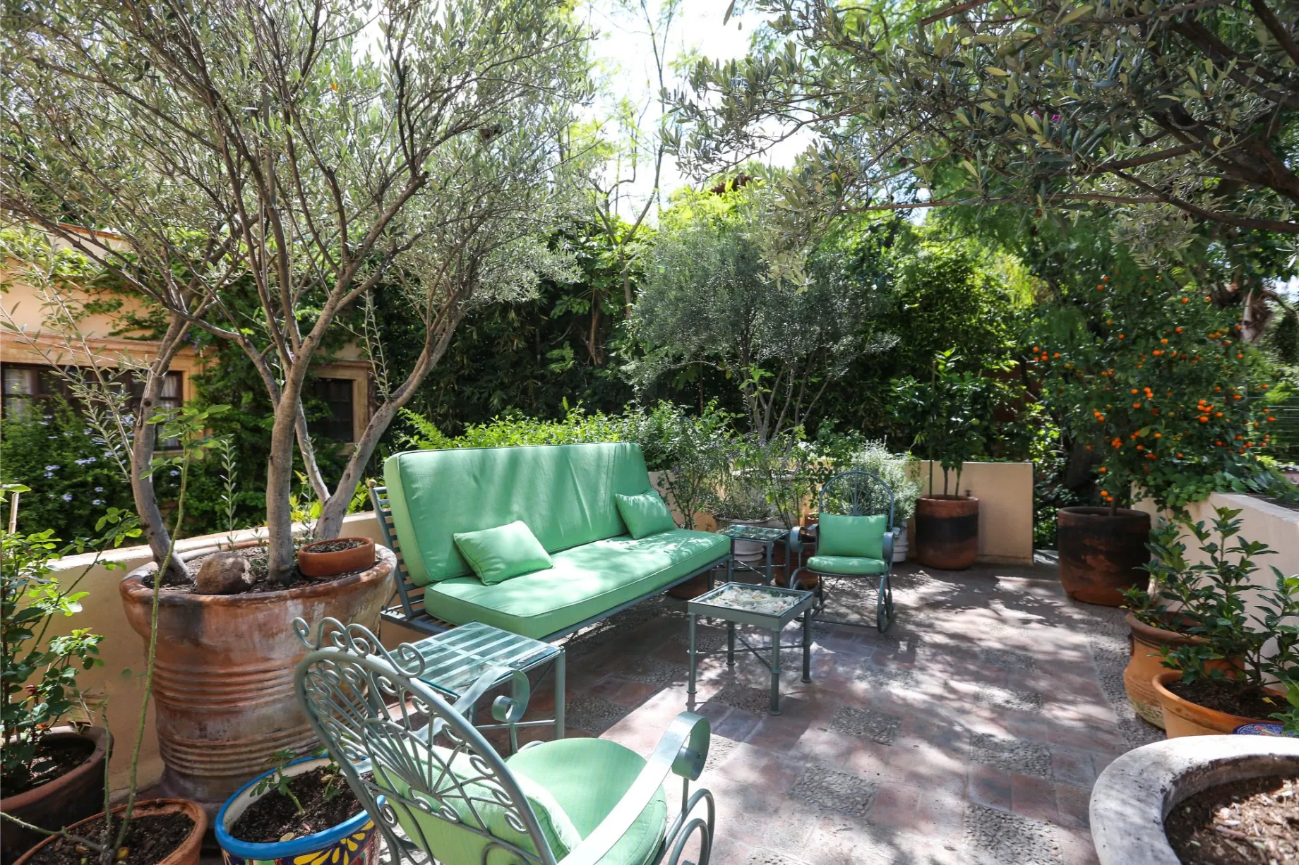 Casa Privada Baeza, garden terrace with a green outdoor sofa and potted trees, San Miguel de Allende