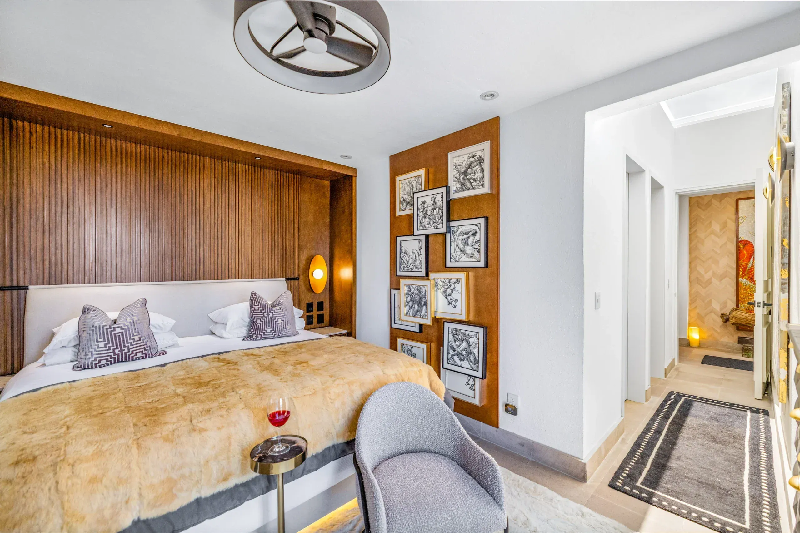 Casa Romana, bedroom with a wood-paneled headboard wall and framed sketches, San Miguel de Allende