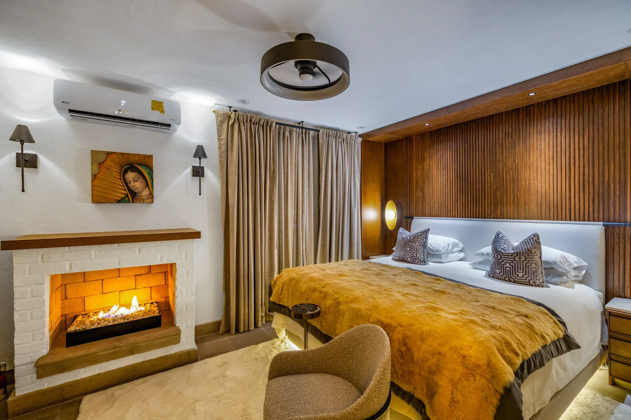 Casa Romana, bedroom with a fireplace and a gold bedspread, San Miguel de Allende