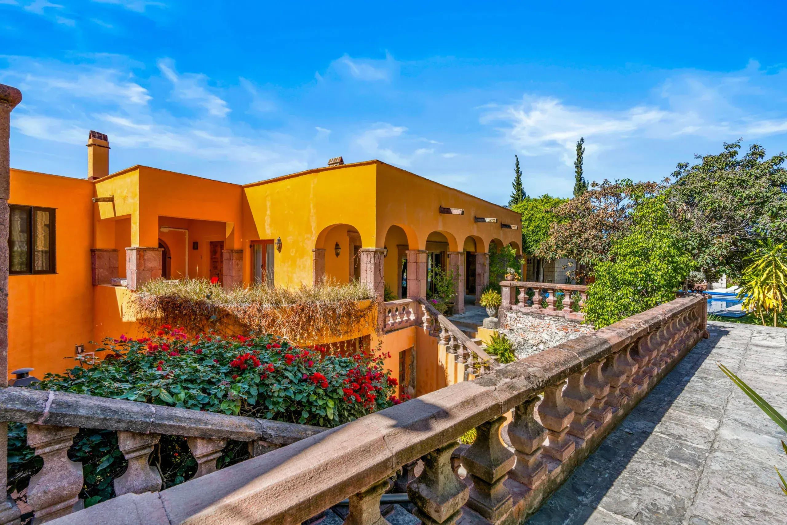 Casa Romana, orange and yellow buildings with a balustrade and flowers, San Miguel de Allende
