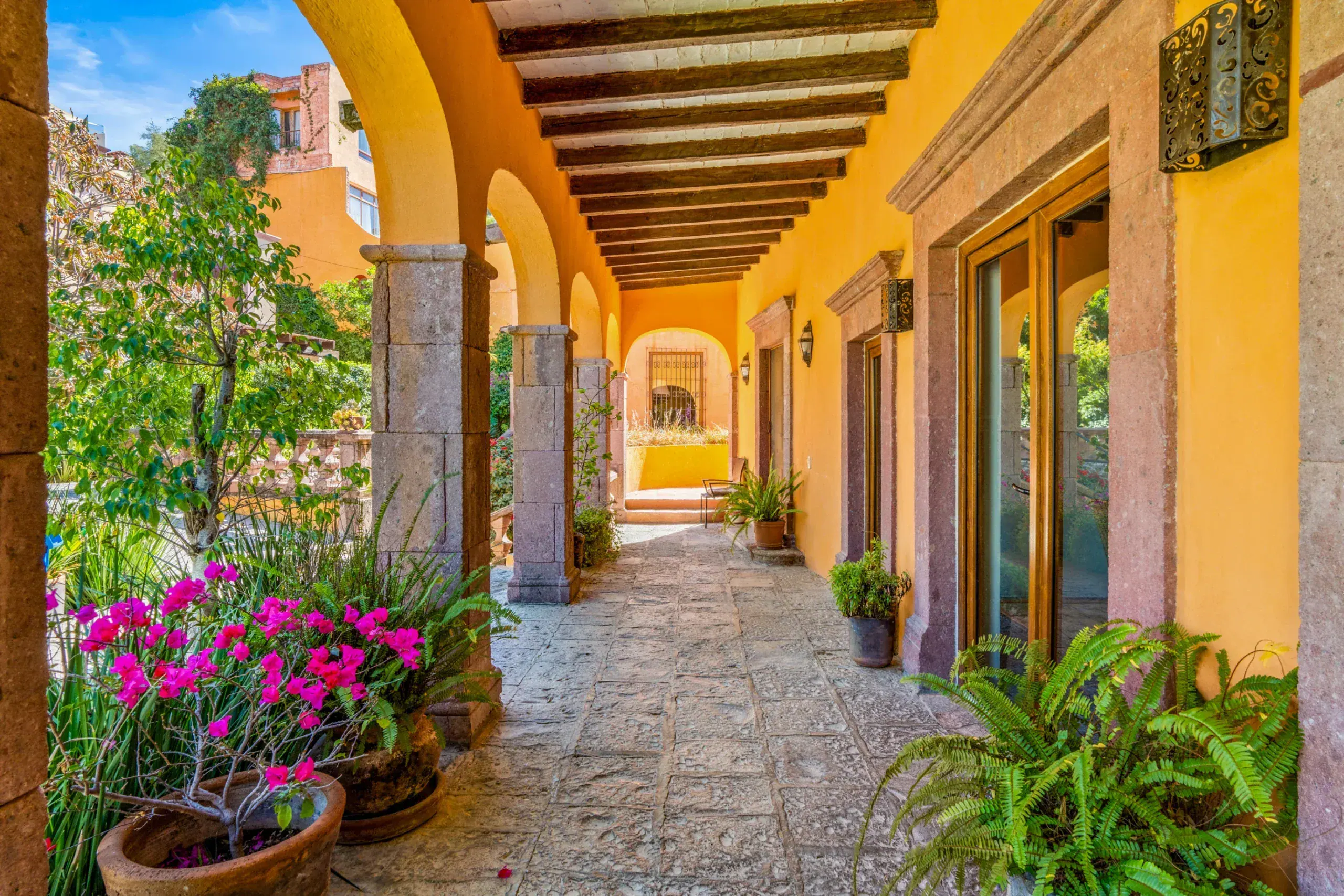 Casa Romana, arcaded walkway with potted flowers and a beamed ceiling, San Miguel de Allende