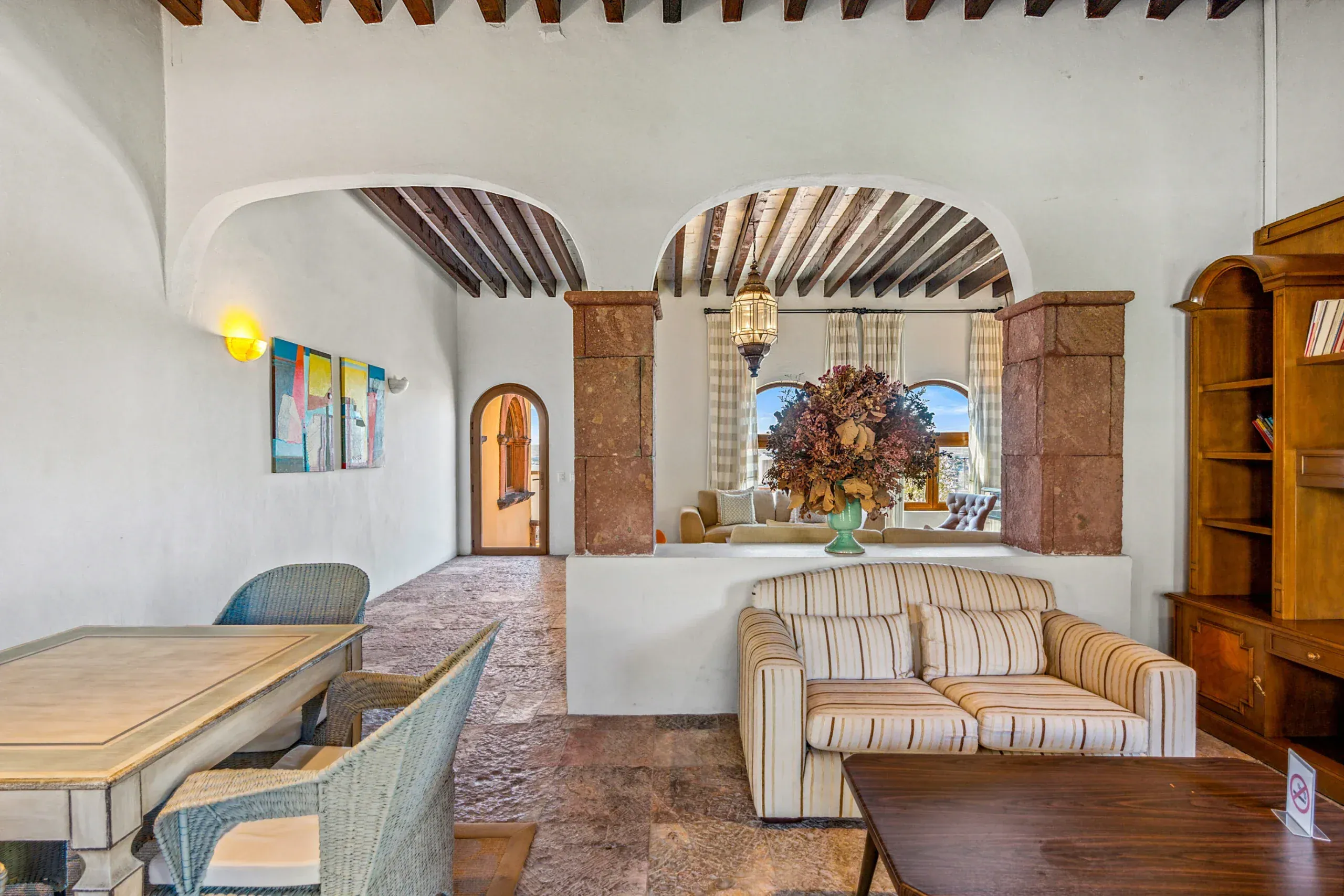 Casa Romana, clubhouse lounge with a beamed ceiling, sofas and bookshelves, San Miguel de Allende