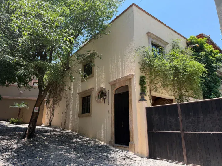 Casa Privada Baeza, cream-colored house exterior with a wooden gate on a gravel street, San Miguel de Allende