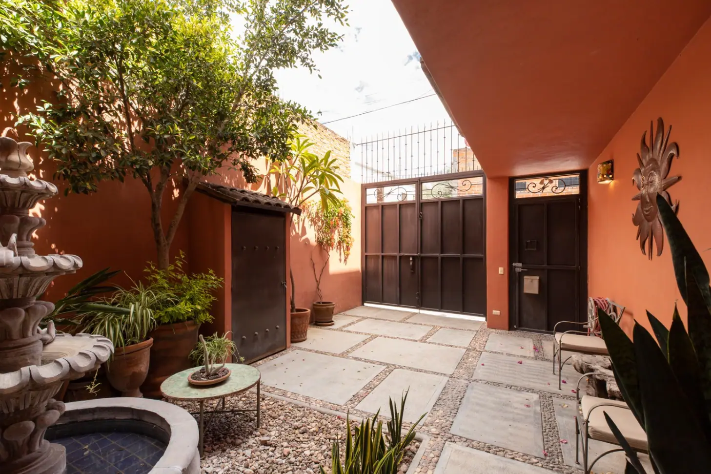 Casa Brillante, courtyard with a stone fountain, plants and a wooden gate, San Miguel de Allende