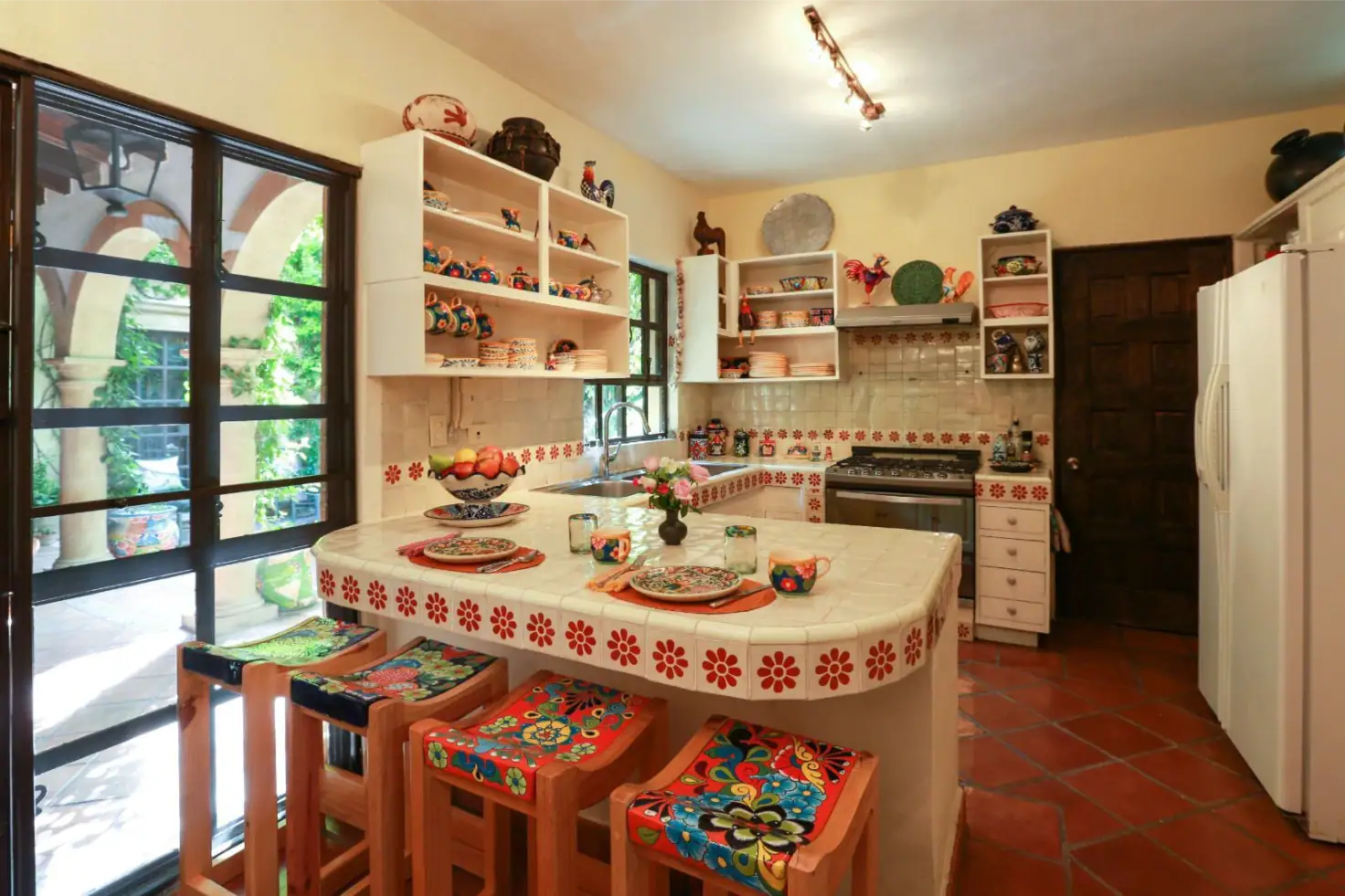 Casa Privada Baeza, kitchen with a tiled island and colorful bar stools, San Miguel de Allende