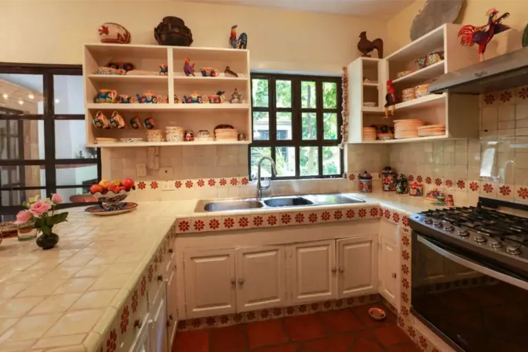 Casa Privada Baeza, kitchen with a tiled counter and open shelves of folk pottery, San Miguel de Allende
