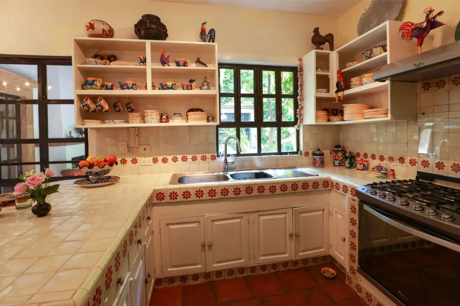 Casa Privada Baeza, kitchen with a tiled counter and open shelves of folk pottery, San Miguel de Allende