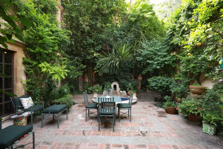 Casa Privada Baeza, central garden courtyard with a fountain, a dining table and brick paving, San Miguel de Allende