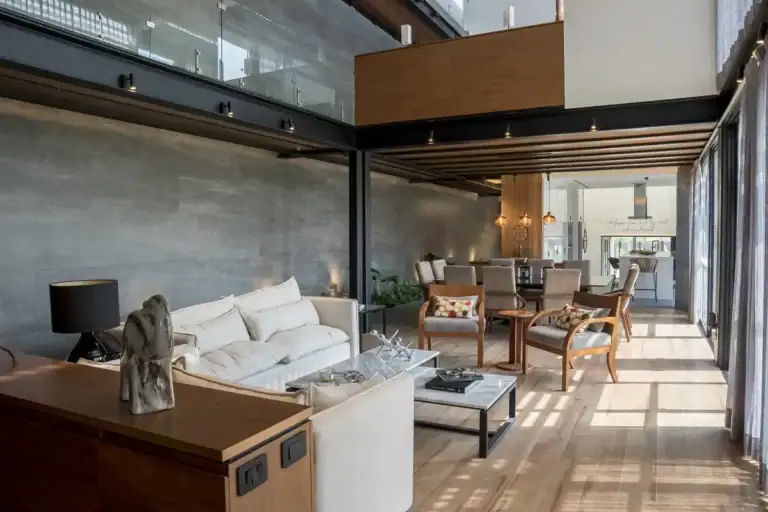 Bright House, double-height living area with a white sofa, a long dining table and a glass-railed mezzanine, San Miguel de Allende