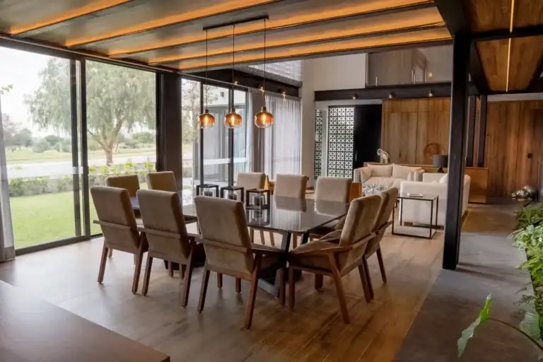 Bright House, dining table with tan chairs, a wood-slat ceiling and glass walls to the golf course lawn, San Miguel de Allende
