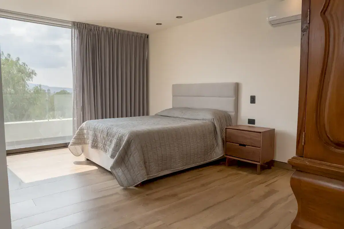 Bright House, bedroom with a twin bed, a carved wood armoire and a floor-to-ceiling window, San Miguel de Allende