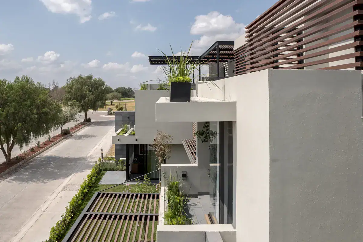 Bright House, side view of the house with wood slat screens, balconies and a street lined with trees, San Miguel de Allende