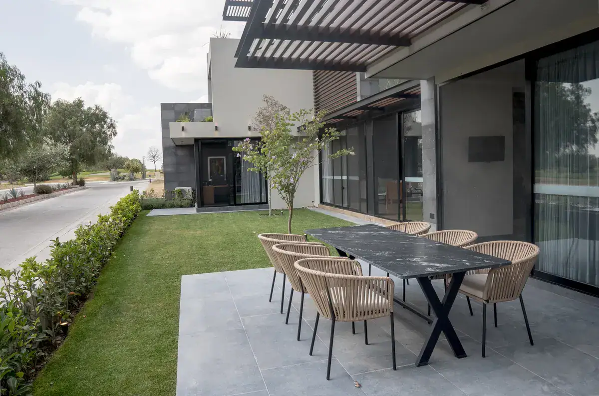 Bright House, garden terrace with a black marble table and woven chairs next to a lawn, San Miguel de Allende