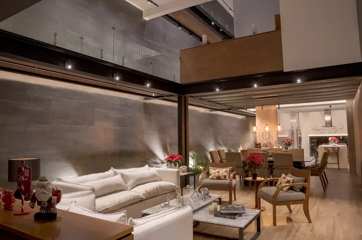 Bright House, living area at dusk with a white sofa, a lit wood ceiling and a dining table, San Miguel de Allende