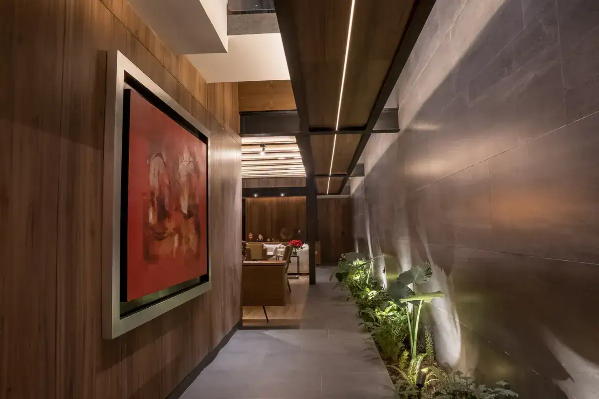 Bright House, entry corridor with a large red painting, a wood wall and a stone-textured wall with a planter, San Miguel de Allende