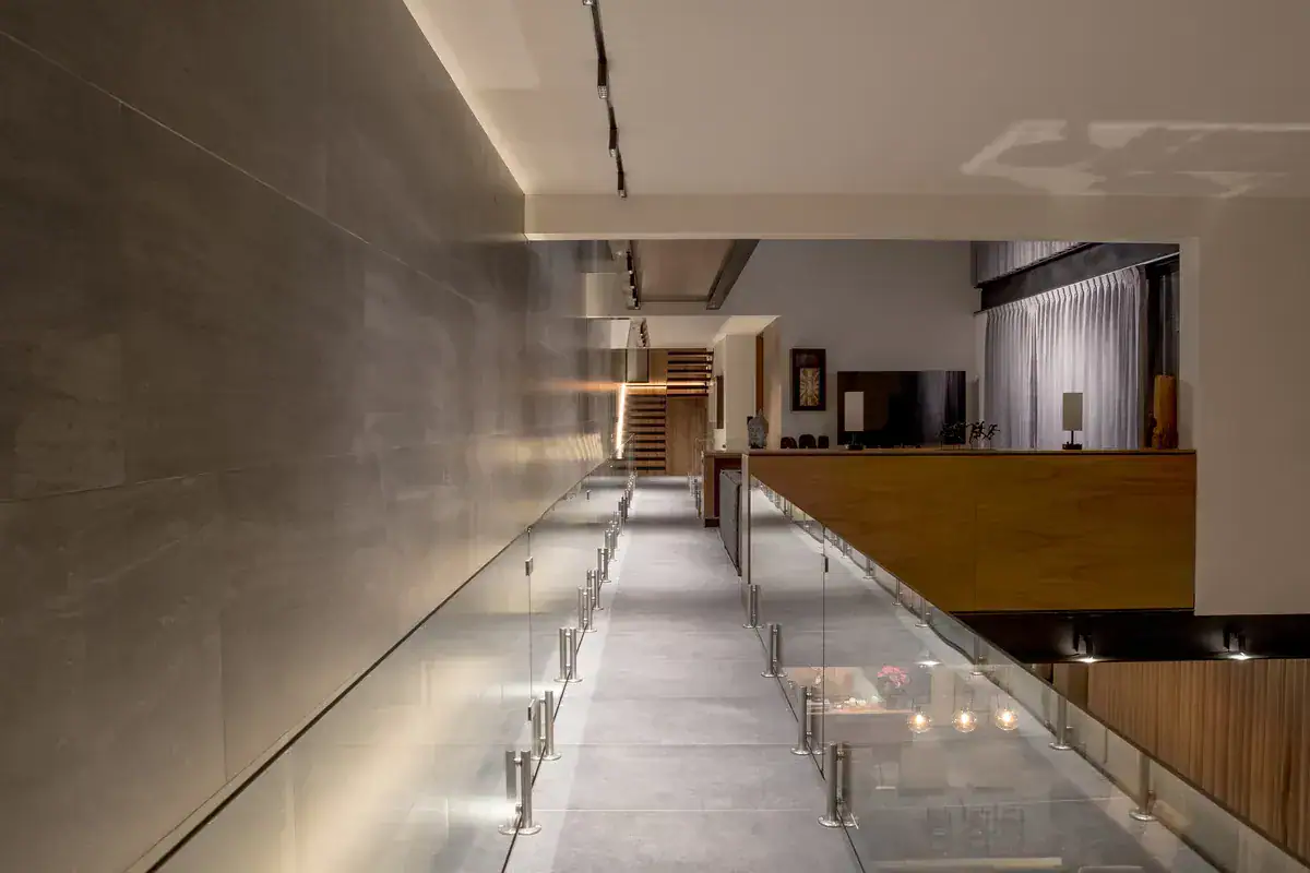 Bright House, walkway with a glass balustrade leading toward the living room at night, San Miguel de Allende