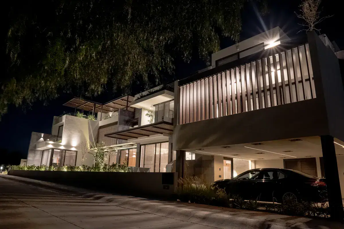 Bright House, street view of the house at night with a lit carport and neighboring homes, San Miguel de Allende