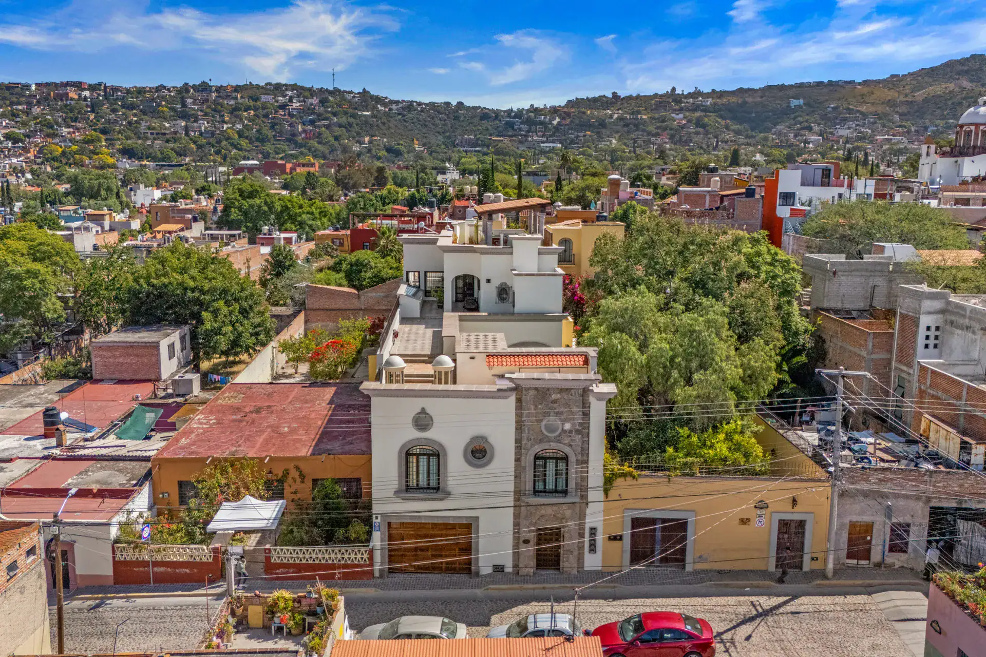 Casa 28 de Abril Norte, aerial view of the street facade, rooftop terrace and the hills of San Miguel de Allende behind