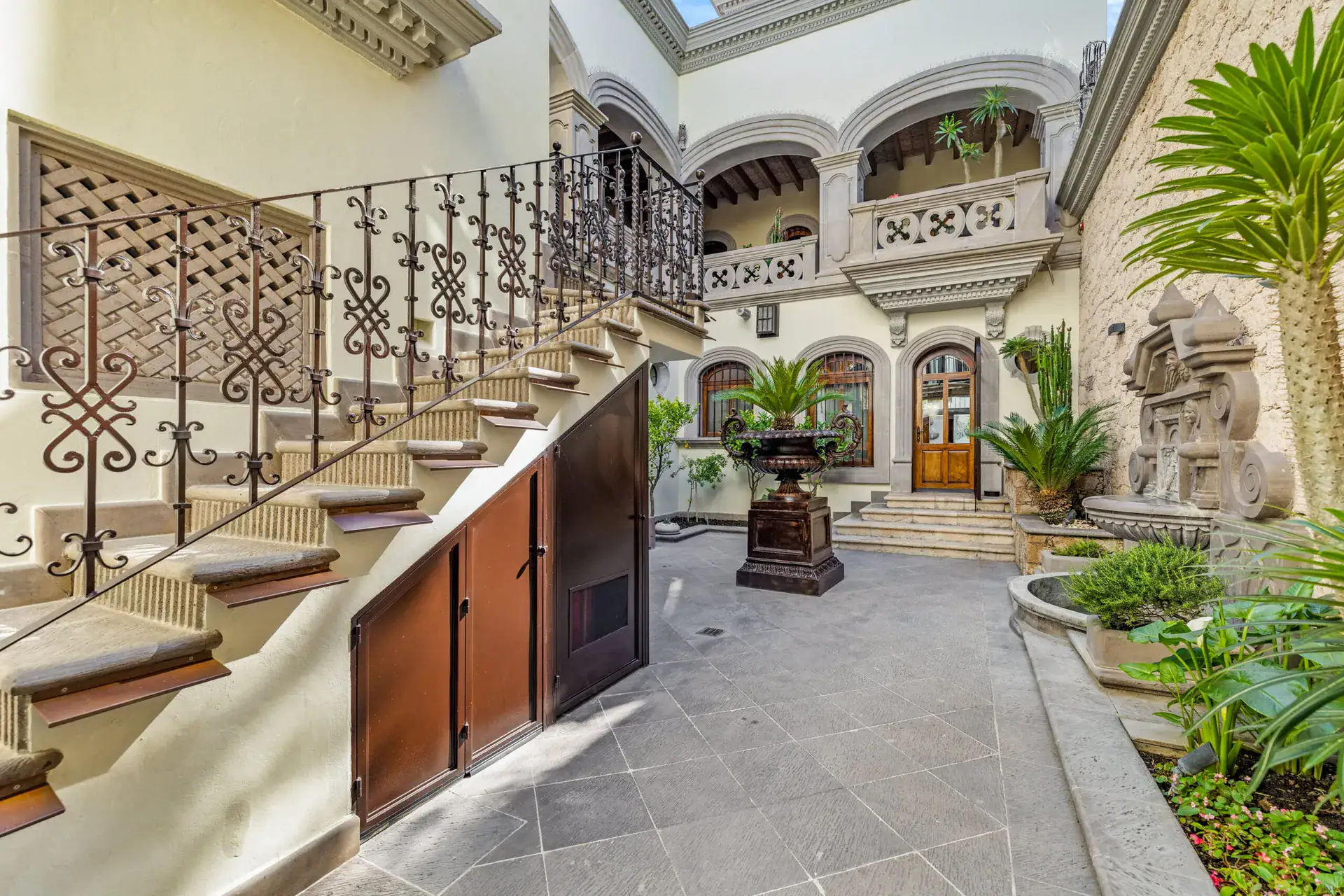 Casa 28 de Abril Norte, interior courtyard with an iron-railed staircase, planters and arched doorways, San Miguel de Allende