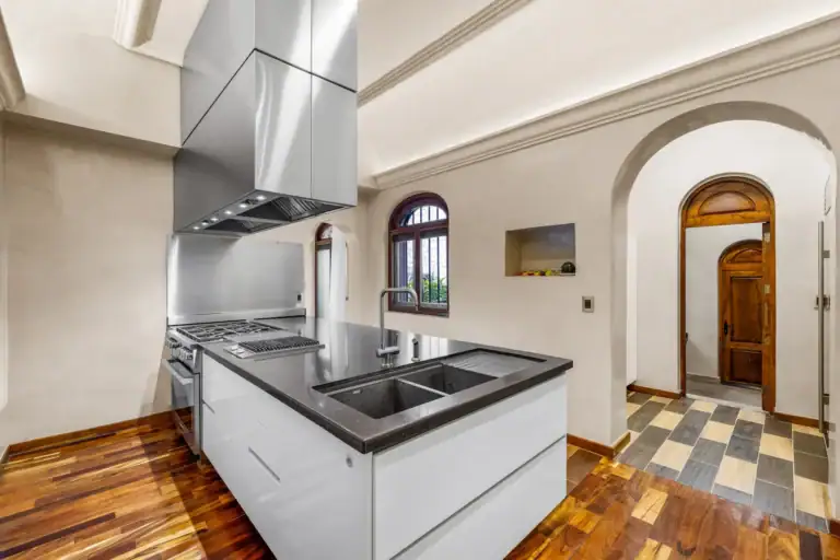 Casa 28 de Abril Norte, modern kitchen with a white island, black counter and a stainless steel range hood, San Miguel de Allende