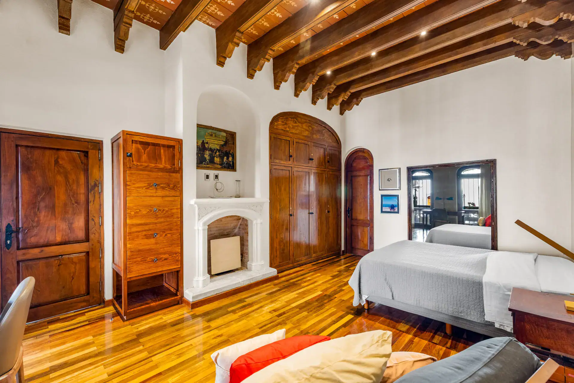 Casa 28 de Abril Norte, bedroom with a stone fireplace niche, carved wood doors and a beamed ceiling, San Miguel de Allende