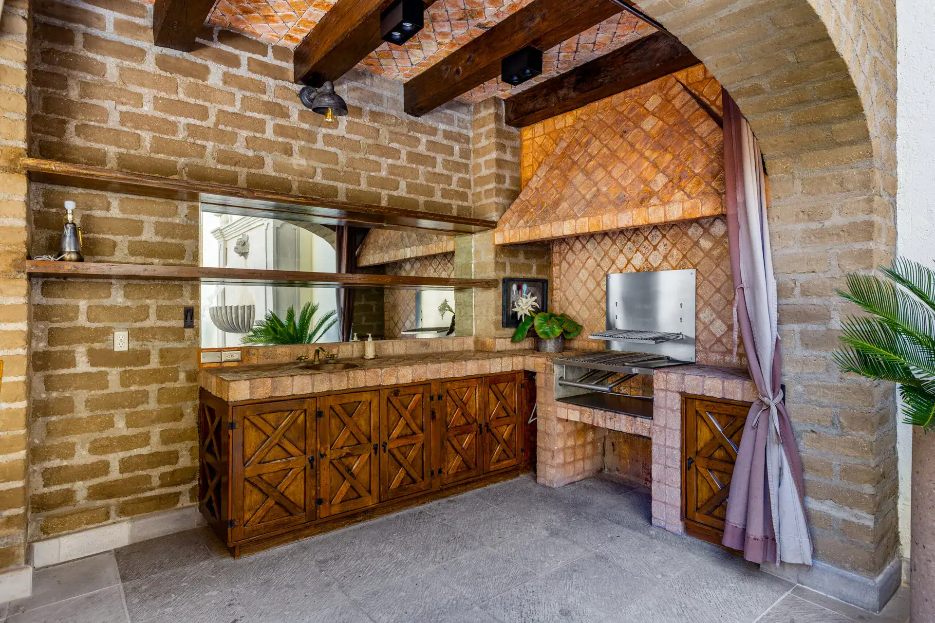 Casa 28 de Abril Norte, outdoor kitchen with a brick arch, wood cabinets and a built-in grill, San Miguel de Allende