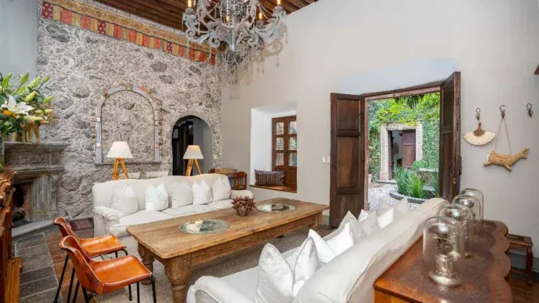 Casa Adelita, living room with a stone wall, white sofas and a crystal chandelier, San Miguel de Allende