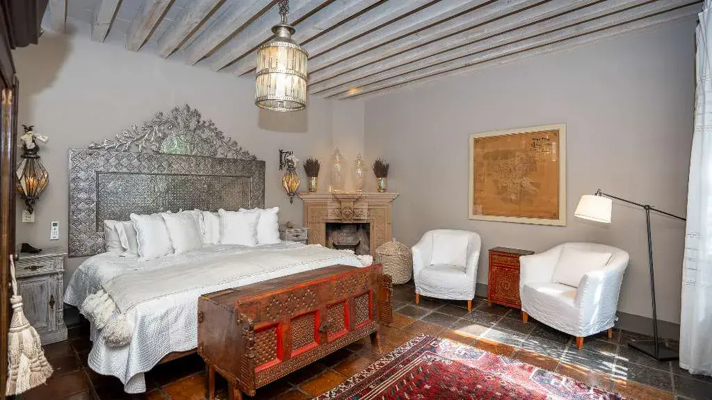 Casa Adelita, primary bedroom with an embossed metal headboard and a stone fireplace, San Miguel de Allende