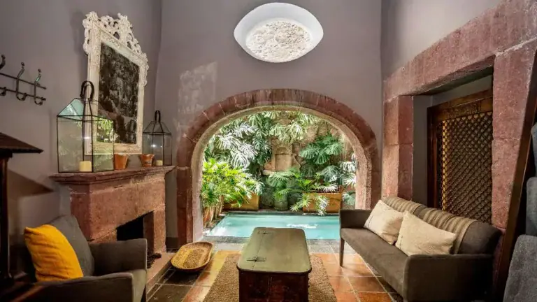 Casa Adelita, living room with a gray sofa, fireplace and a view to the courtyard pool, San Miguel de Allende